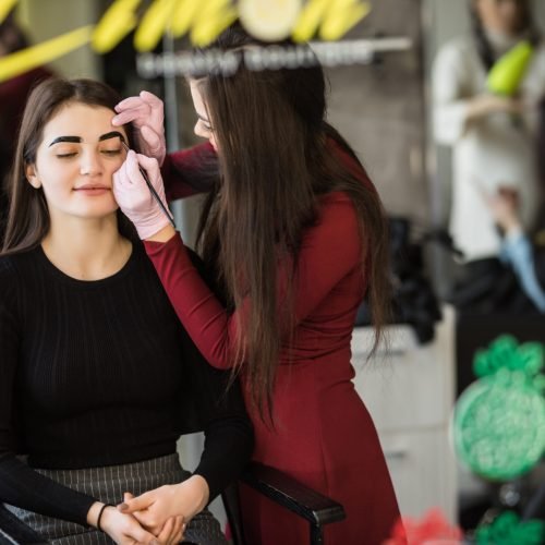 Two girls are doing make-up in front of professional mirror